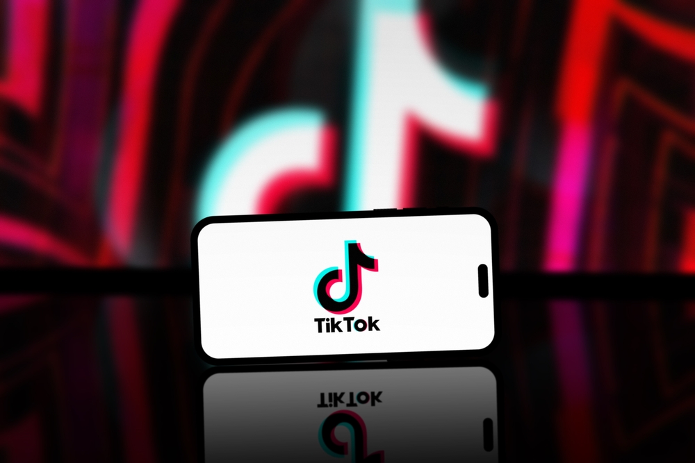 La aplicación TikTok se muestra en la pantalla del teléfono inteligente, el logotipo de TikTok está borroso en el fondo